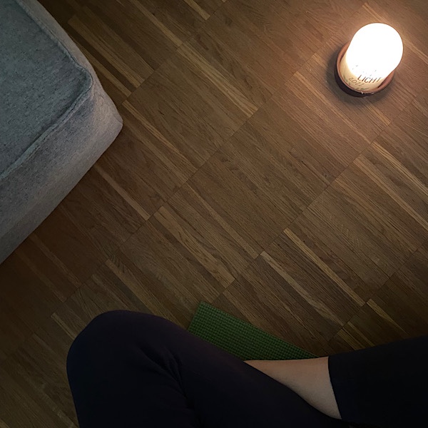 Frau sitzt auf Boden mit Kerze