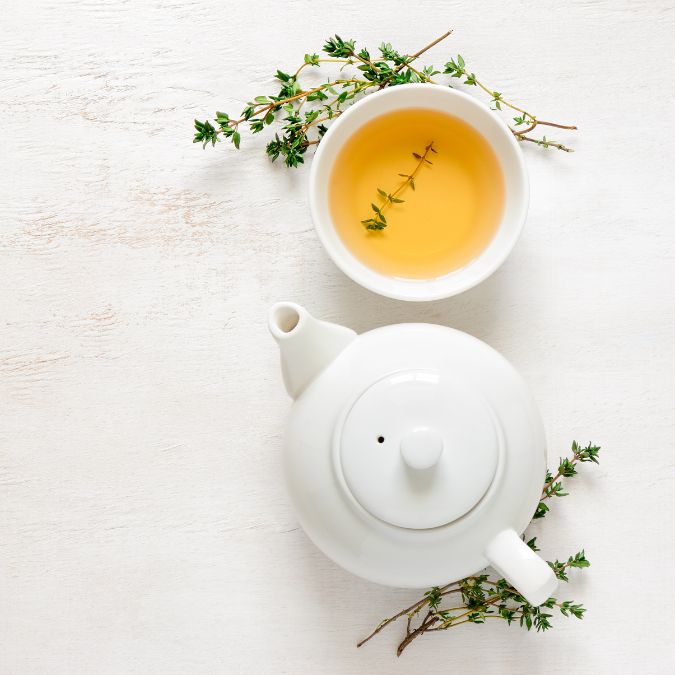 Teekanne und Tasse Tee auf weißem Tisch