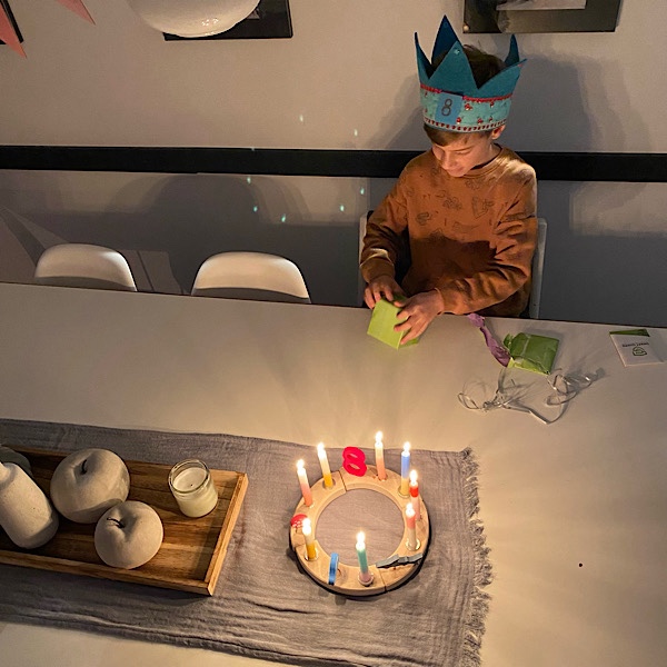 Geburtstagskind am Tisch mit Kerzenkranz zum 8. Geburtstag